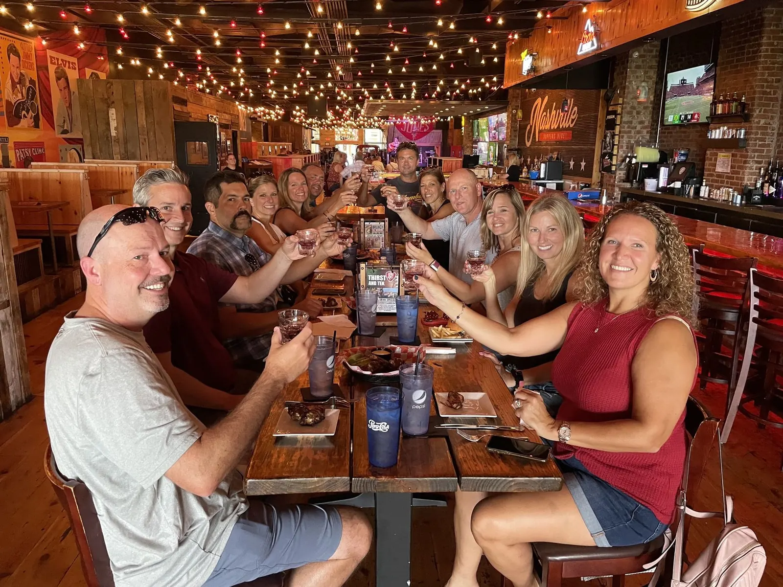 A team raising their glasses together around a long table on a private A Little Local Flavor food tour in downtown Nashville